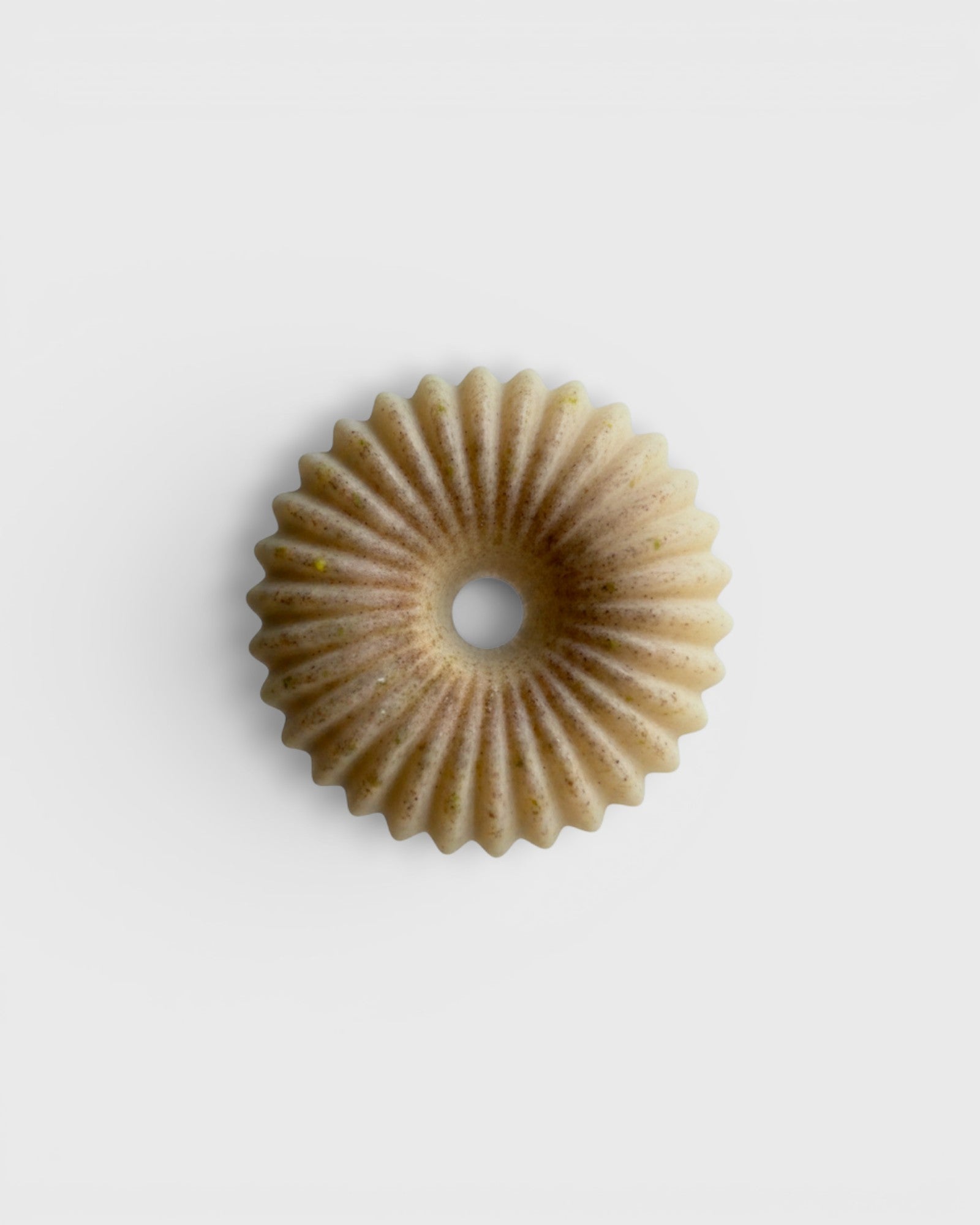 JONES + CO lülala vetiver and makrut lime soap bar with a circular, fluted design and natural clay texture.