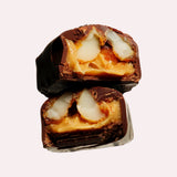 JONES + CO maple macadamia caramel chocolate piece cut in half showing chewy caramel and roasted macadamia nuts
