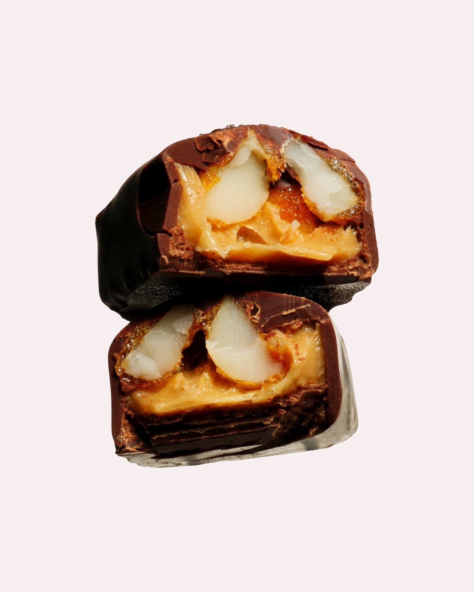 JONES + CO maple macadamia caramel chocolate piece cut in half showing chewy caramel and roasted macadamia nuts