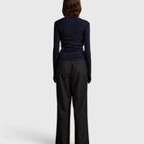Back view of a model wearing the JONES + CO Margot Wrap Top in midnight blue knit with long sleeves.