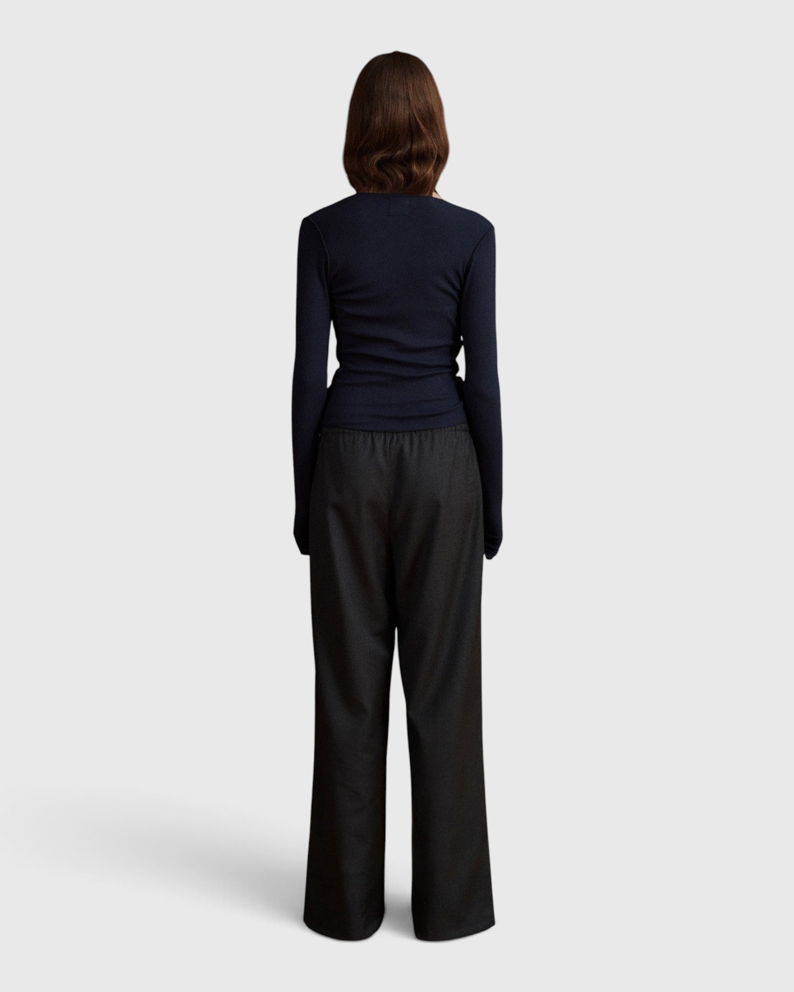 Back view of a model wearing the JONES + CO Margot Wrap Top in midnight blue knit with long sleeves.