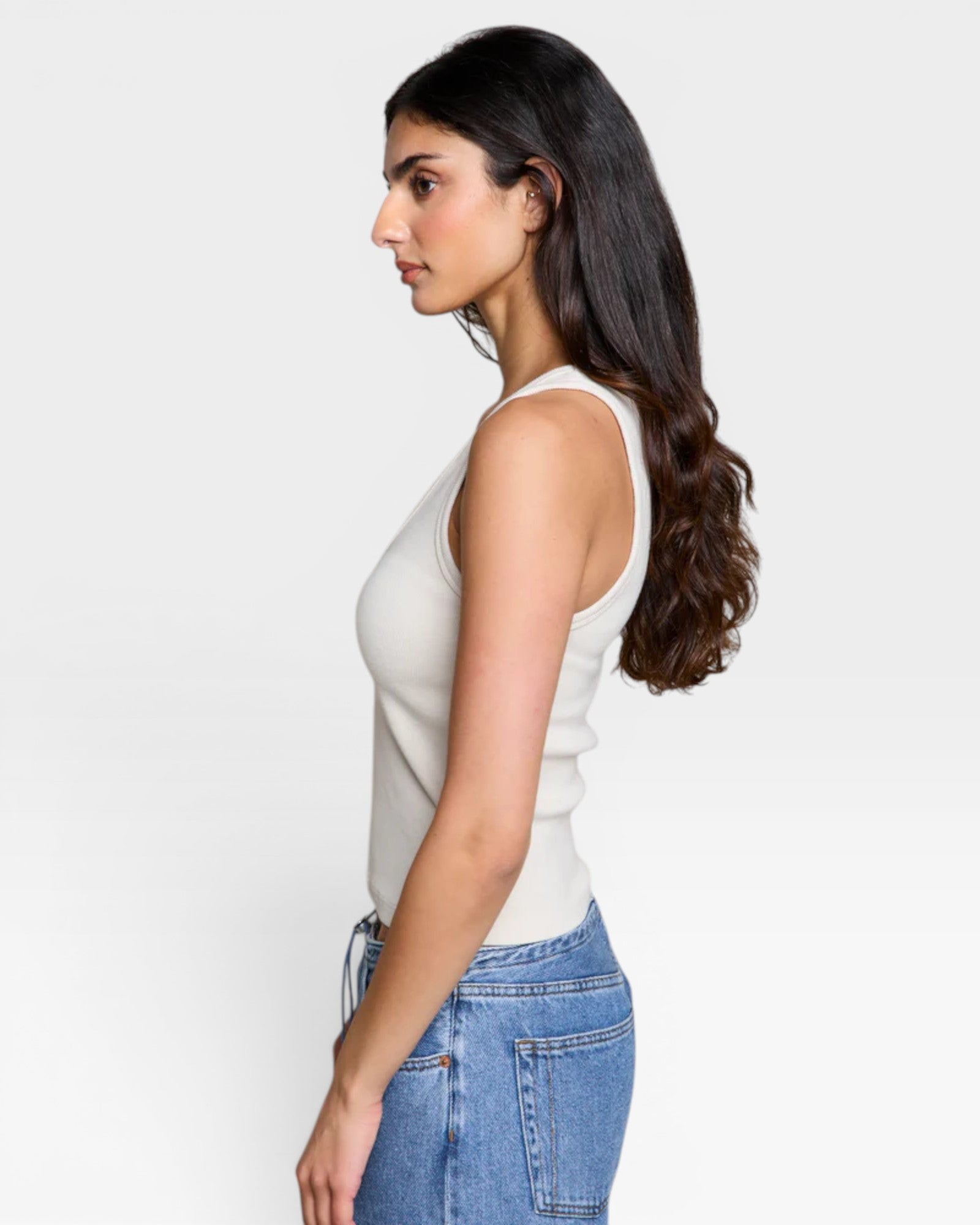 JONES + CO Maria V Neck tank top in sugar white ribbed fabric with a v-neckline, worn by a model with dark hair.