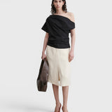 Model wearing a black JONES + CO Mata one-shoulder organic cotton blouse with an asymmetric neckline.