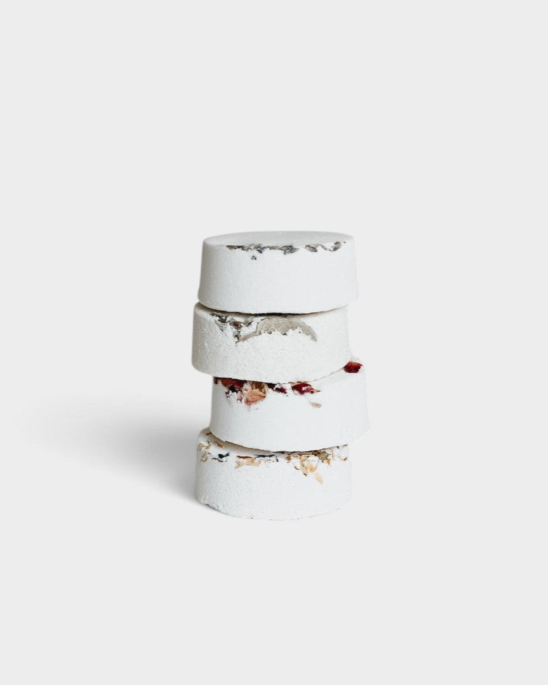 JONES + CO menthol eucalyptus shower steamer stack with dried botanical petals on a white background