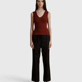 Model wearing JONES + CO merlot ribbed knit Kana Tank with deep scoop neckline and fluid fit against grey background
