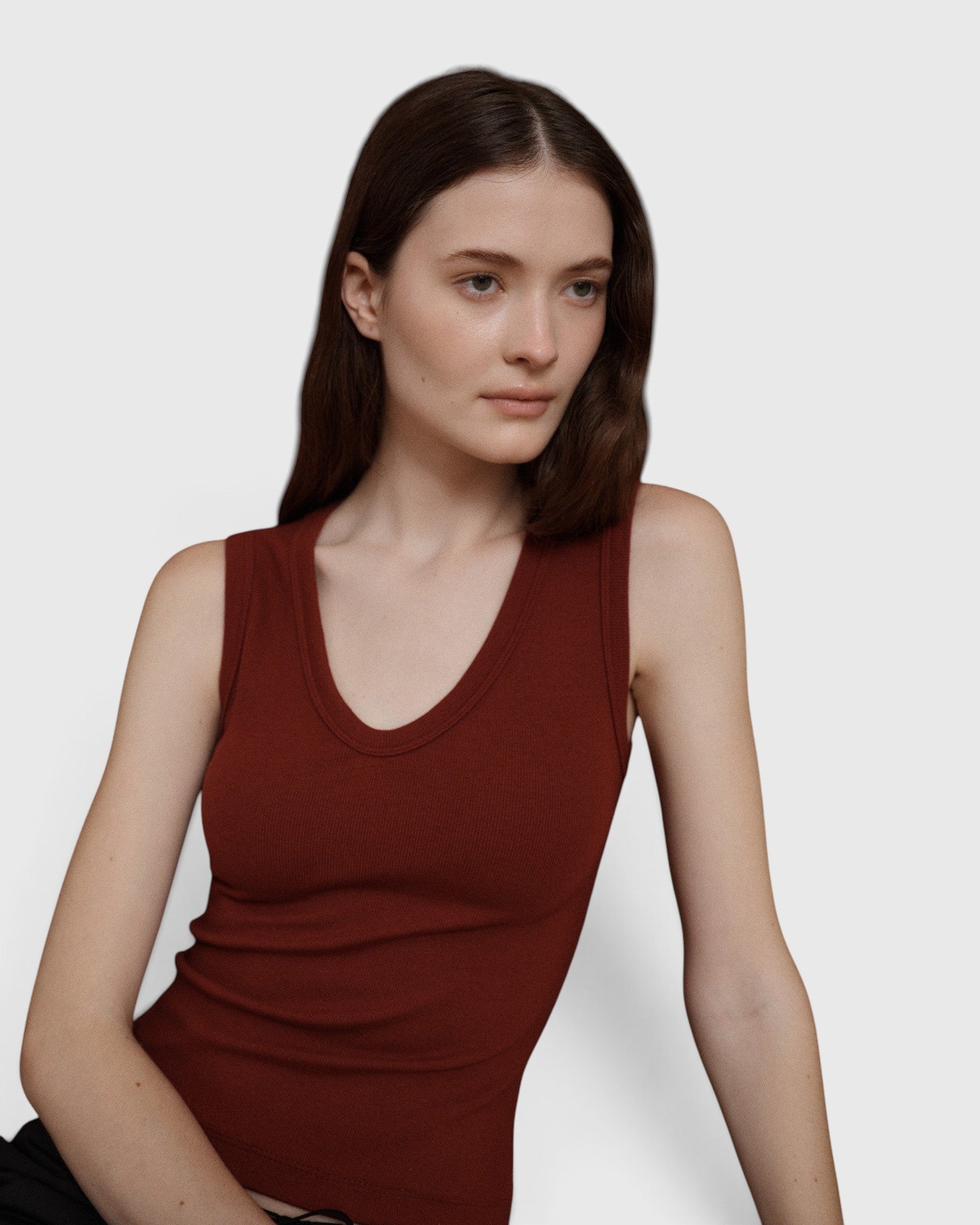 Model wearing a JONES + CO Kana Tank in merlot, featuring a deep scoop neckline and finely ribbed knit fabric.