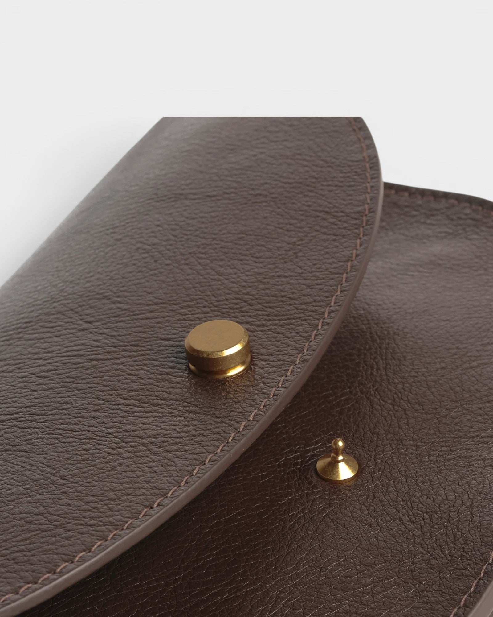 JONES + CO Mezzo crossbody bag in Chaga brown leather with brass hardware and stitching detail.