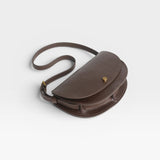 JONES + CO Mezzo crossbody bag in dark brown textured leather with brass hardware and adjustable strap.
