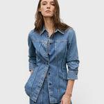 JONES + CO mid blue denim shirt with curved seams, pointed collar, and button-front closure on a female model.