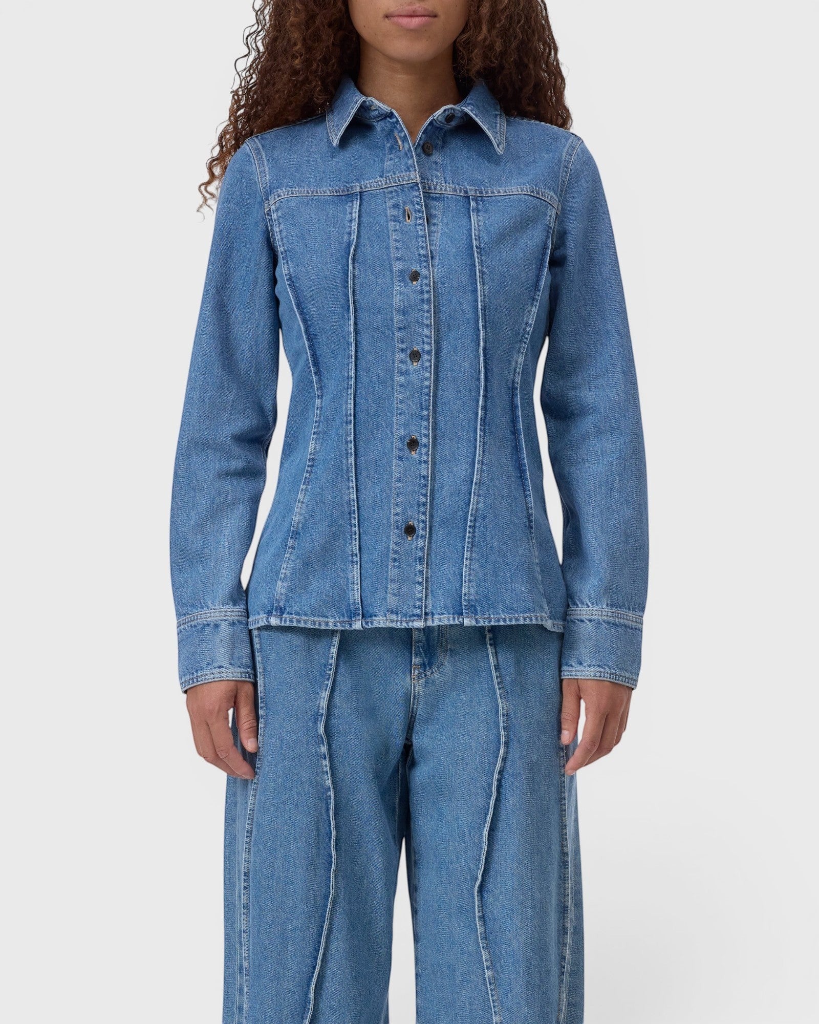 JONES + CO mid-blue denim shirt with curved seams, pointed collar, and button-front closure on a model.