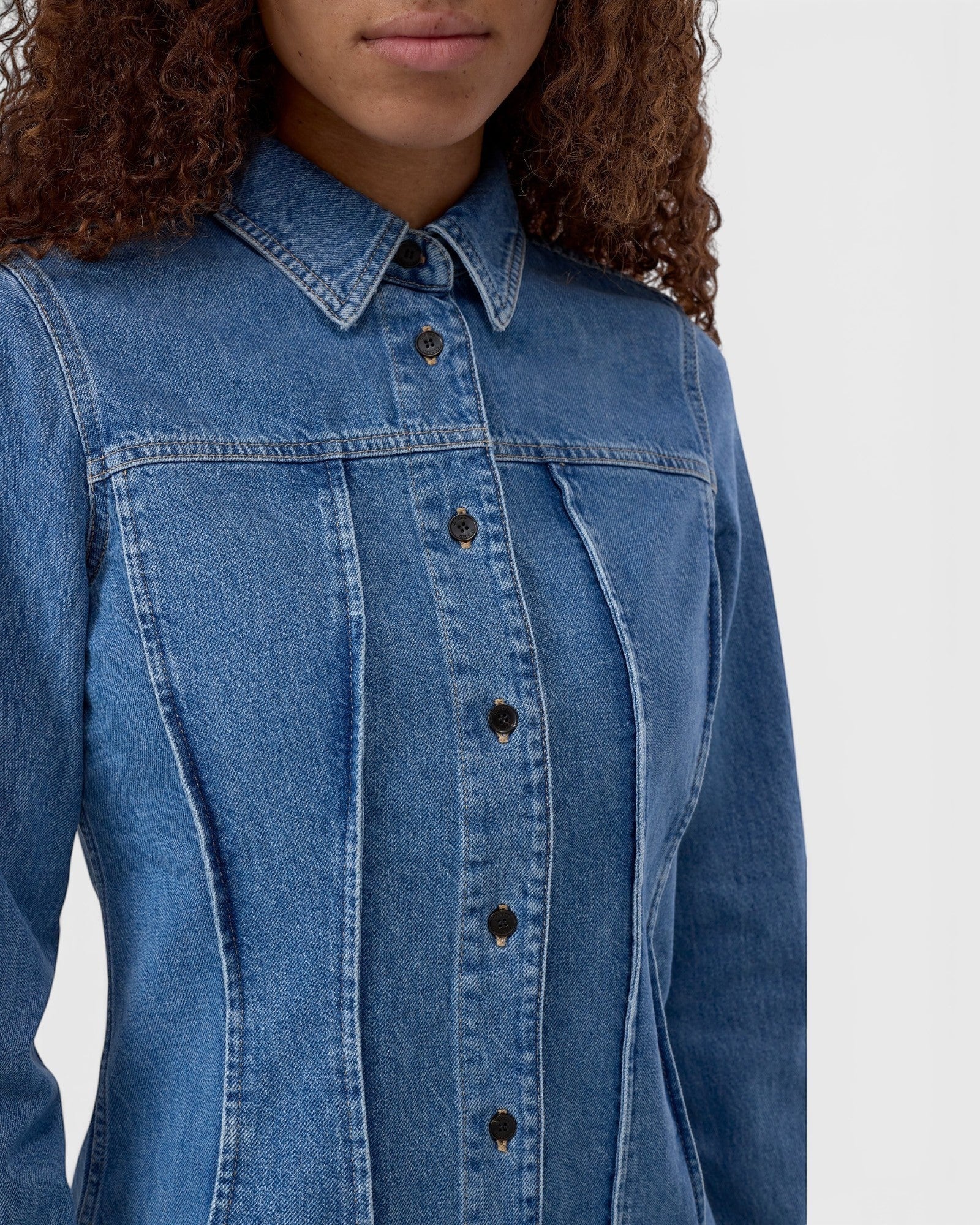 JONES + CO mid-blue denim shirt with pointed collar, button-front closure, and distinctive curved seaming details.