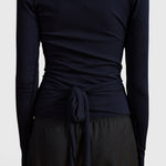 Back view of JONES + CO Margot wrap top in midnight blue knit fabric with a tied waist detail.