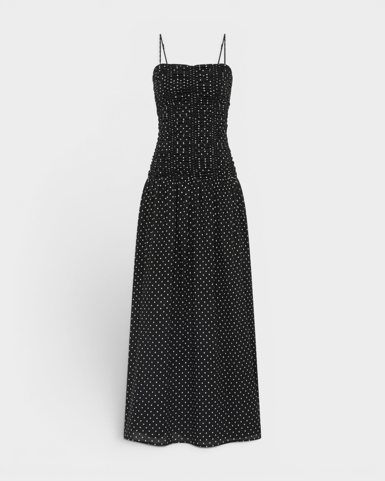 JONES + CO Mira maxi dress in black with off-white polka dots, featuring a ruched bodice and thin spaghetti straps.