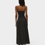 Back view of JONES + CO Mira maxi dress in black with off-white polka dots, featuring spaghetti straps and smocking.