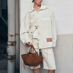 JONES + CO Mochi tote bag in cognac Italian suede with organic curves and knot details held by a model in cream denim