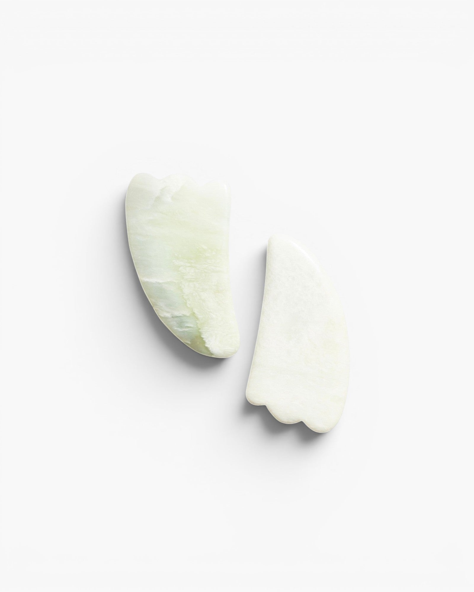 JONES + CO natural jade gua sha stones for depuffing and improving circulation. Light green and white marbled stone.