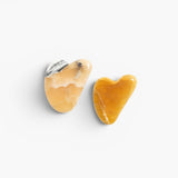 JONES + CO natural gua sha stones in warm yellow and white with black veining, heart-shaped for facial massage.