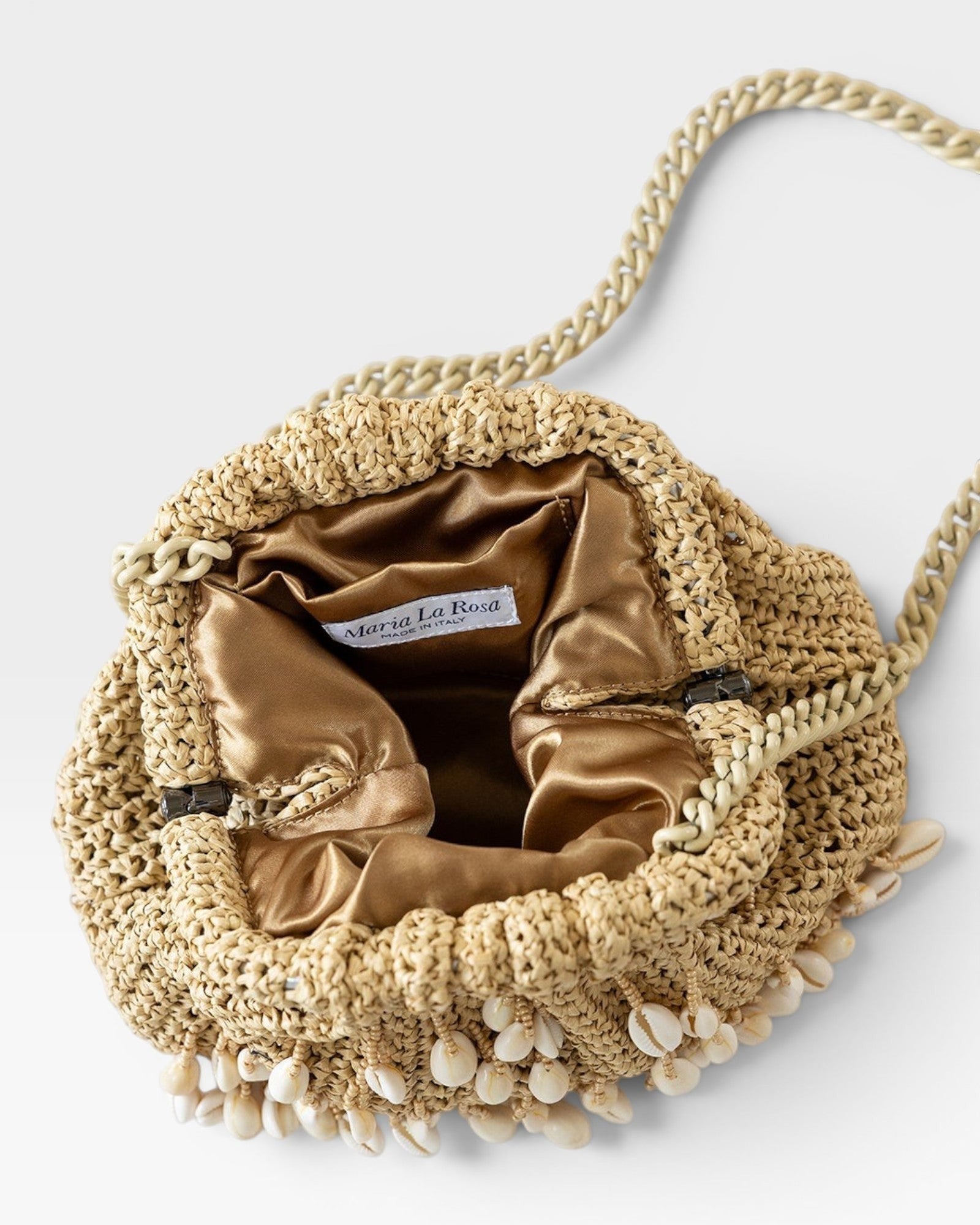 JONES + CO natural raffia crochet mini clutch with shell embellishments and gold satin lining. Features a chain strap.