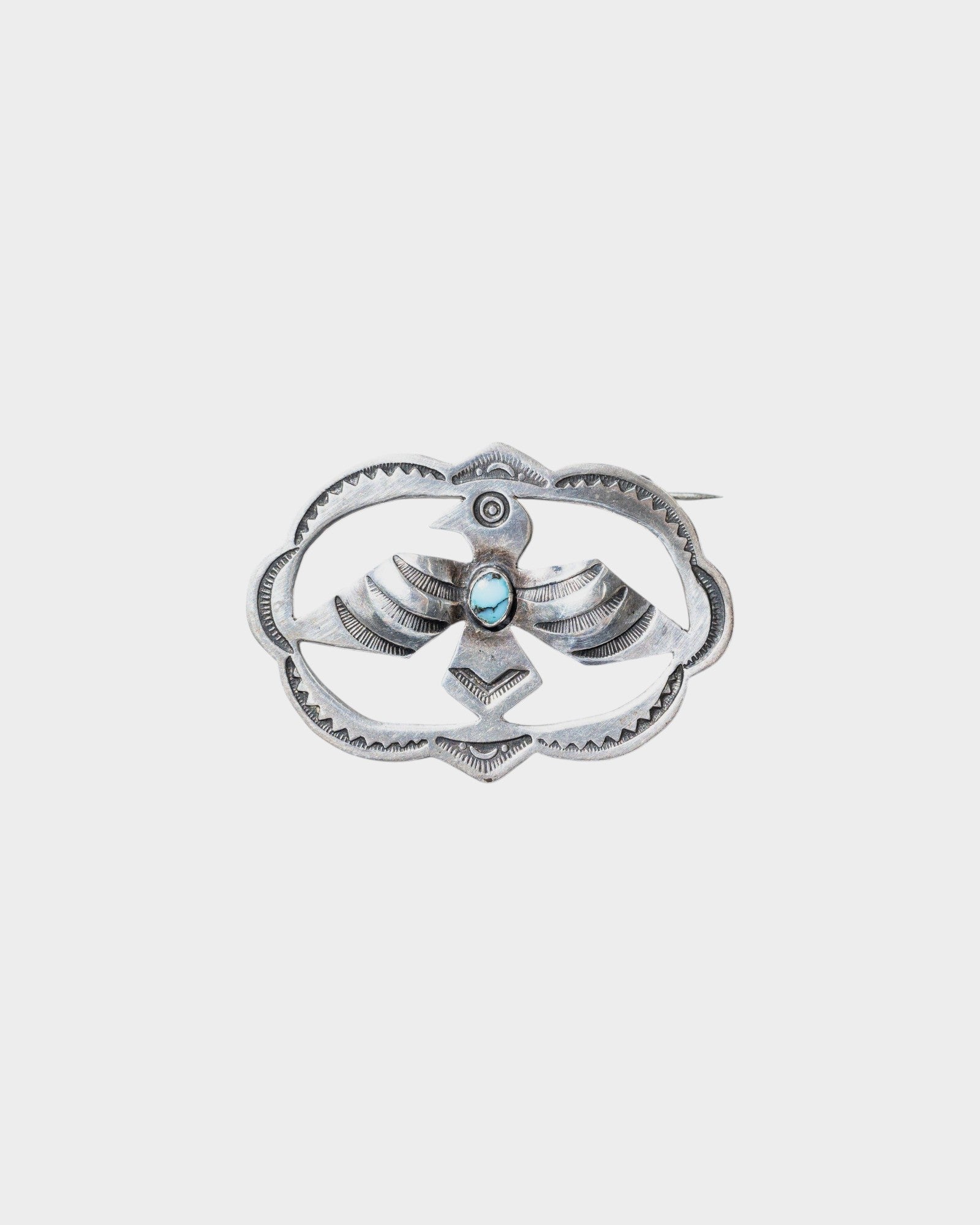 JONES + CO Vintage Navajo Thunderbird brooch in sterling silver with turquoise accent. Oval shape with detailed wings and feathers.