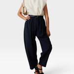 JONES + CO navy Brady trousers with a high-waisted, gathered design and tapered cropped leg on a model.
