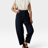 JONES + CO navy Brady trousers with a high-waisted, gathered design and tapered cropped leg on a model.