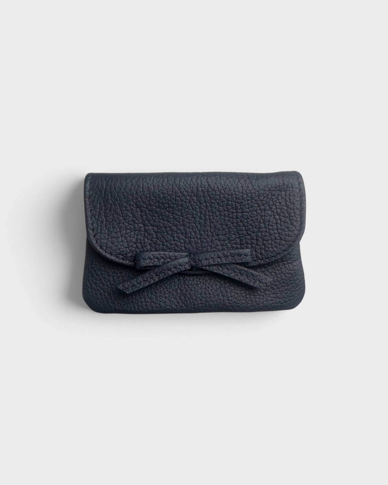 JONES + CO navy blue pebbled leather petite case with a decorative knotted bow and hidden magnetic closure
