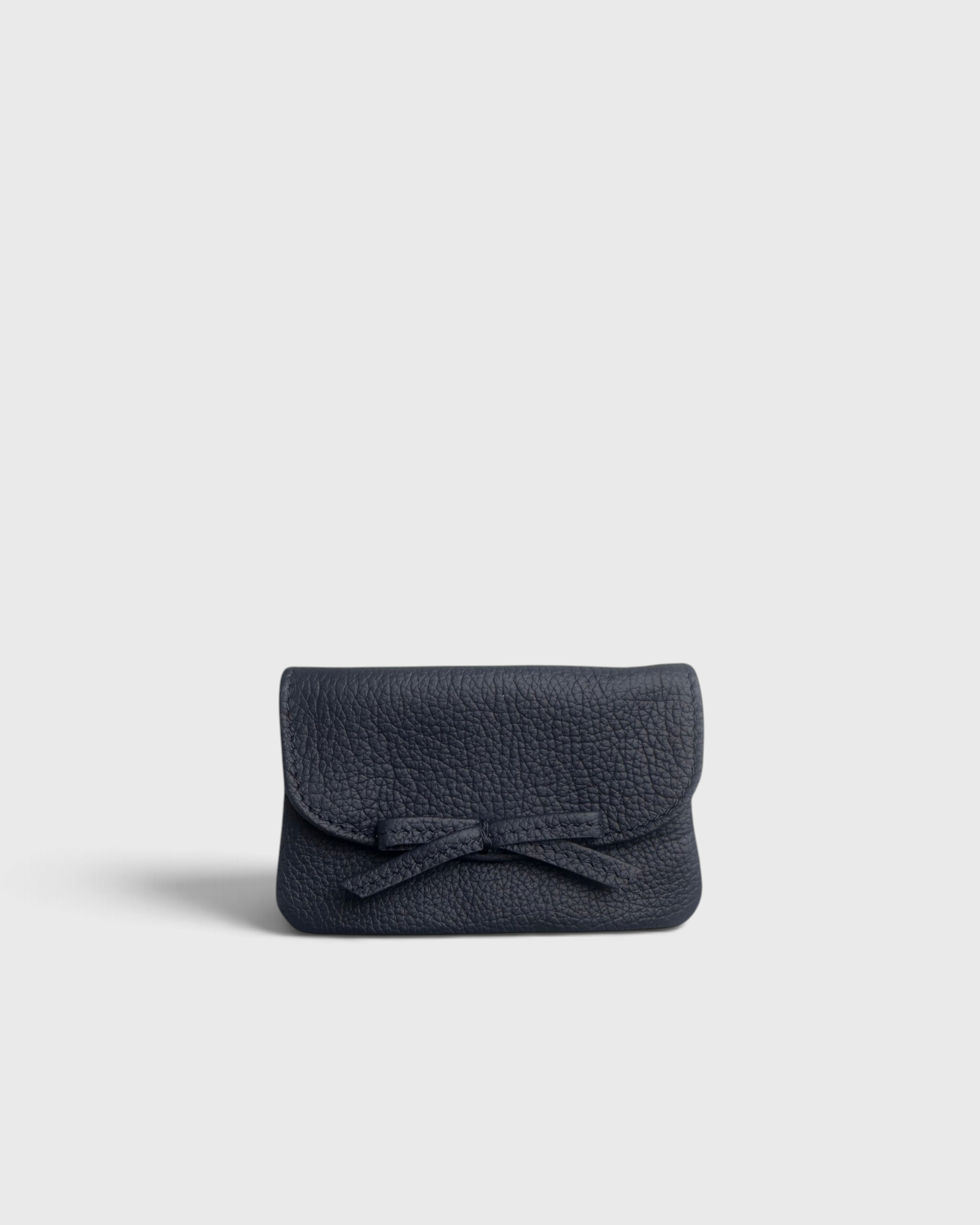 JONES + CO navy blue pebbled leather petite case with a decorative knotted bow and hidden magnetic closure