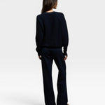 Woman wearing a navy JONES + CO Ziggy sweatshirt and matching trousers, viewed from the back.