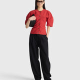JONES + CO Noor red crew-neck top with puff sleeves and front button closure worn with black trousers and sunglasses