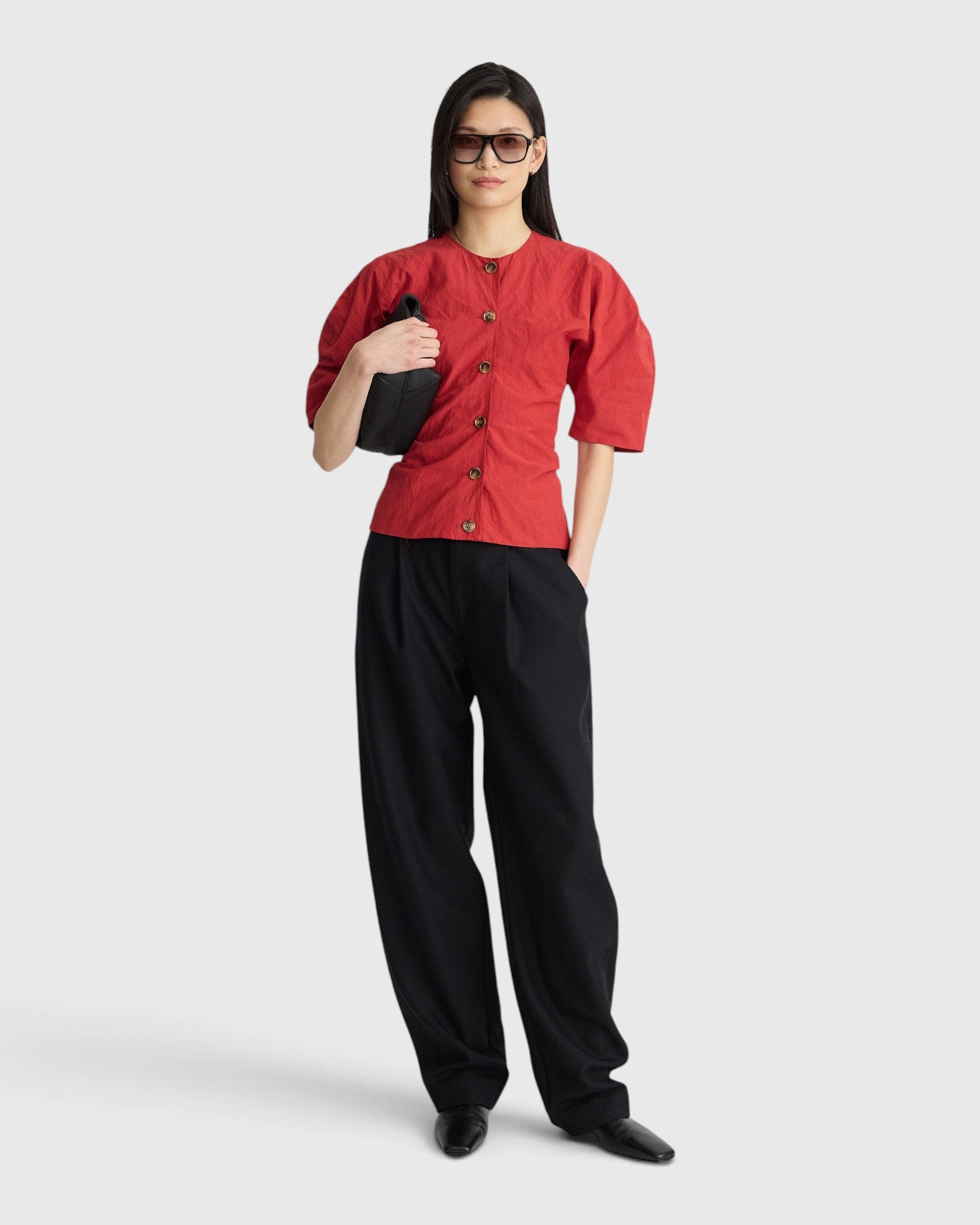 JONES + CO Noor red crew-neck top with puff sleeves and front button closure worn with black trousers and sunglasses