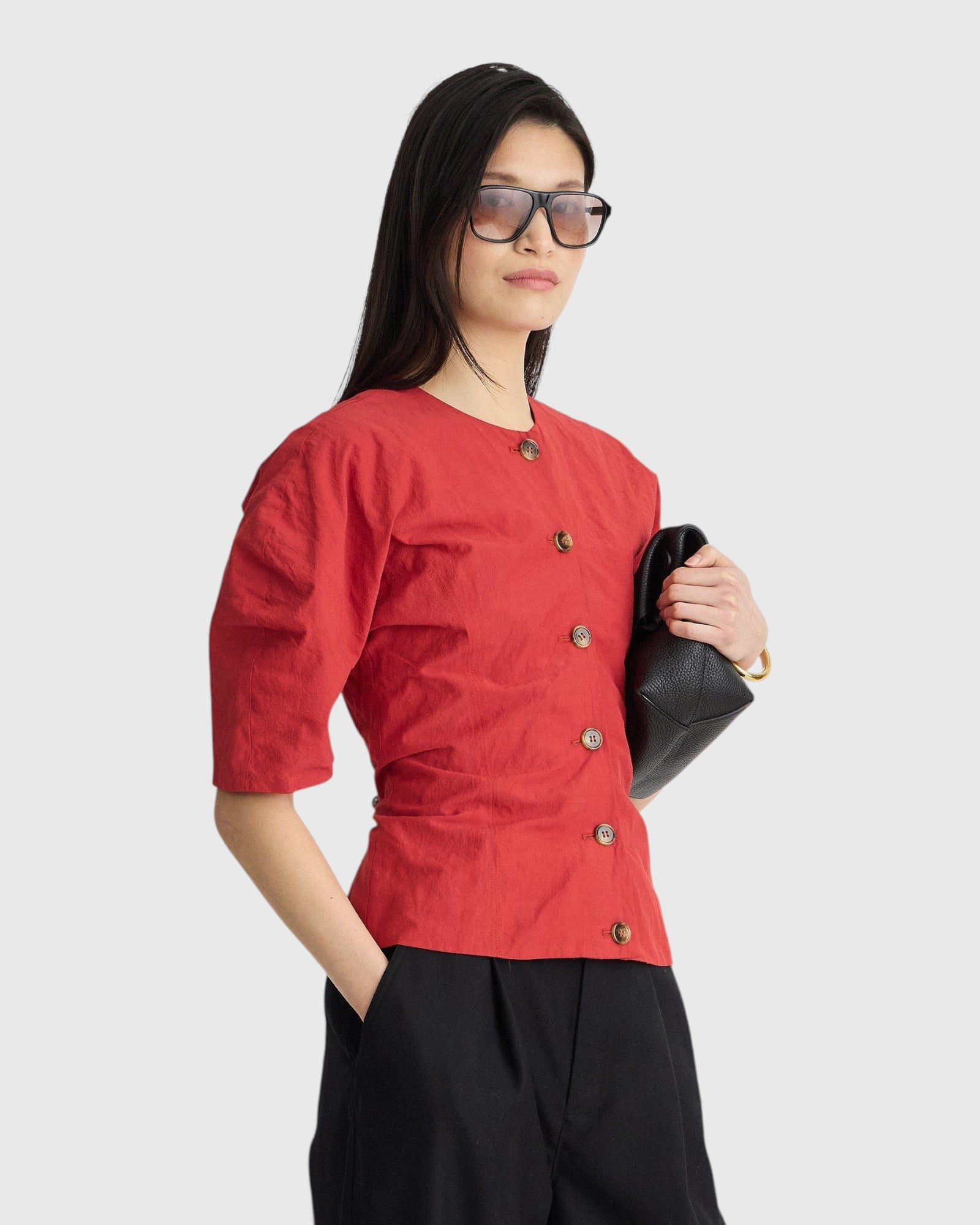 JONES + CO Noor red crew-neck top with button front and short puff sleeves worn by a model with black sunglasses.