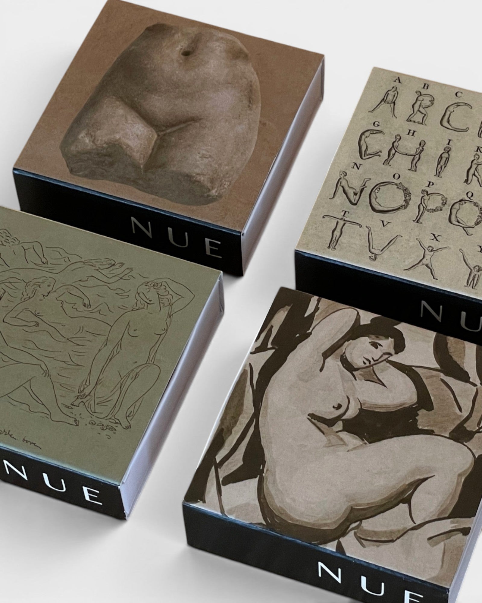 JONES + CO Nue artistic matchboxes featuring classical figure drawings and alphabet illustrations on square boxes.