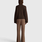 Back view of a model wearing a JONES + CO oak brown cashmere mock-neck sweater with balloon sleeves and matching pants