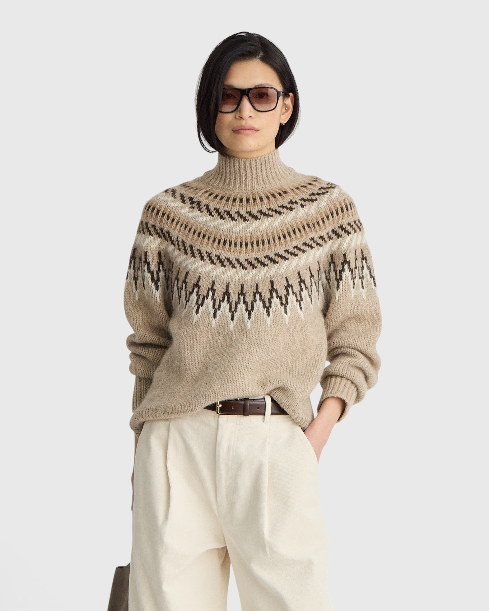 JONES + CO oatmeal Fair Isle mock neck sweater with ribbed trim worn by a model in sunglasses and cream trousers.