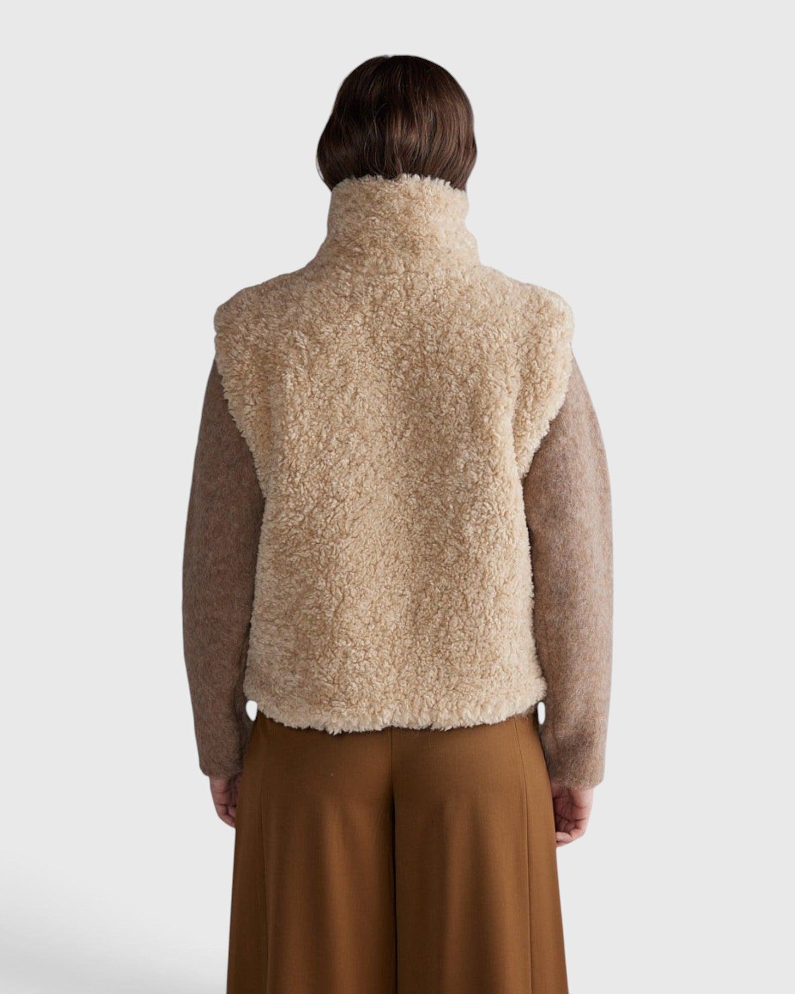 JONES + CO oatmeal high neck reversible faux fur vest worn from the back showing a boxy cropped silhouette