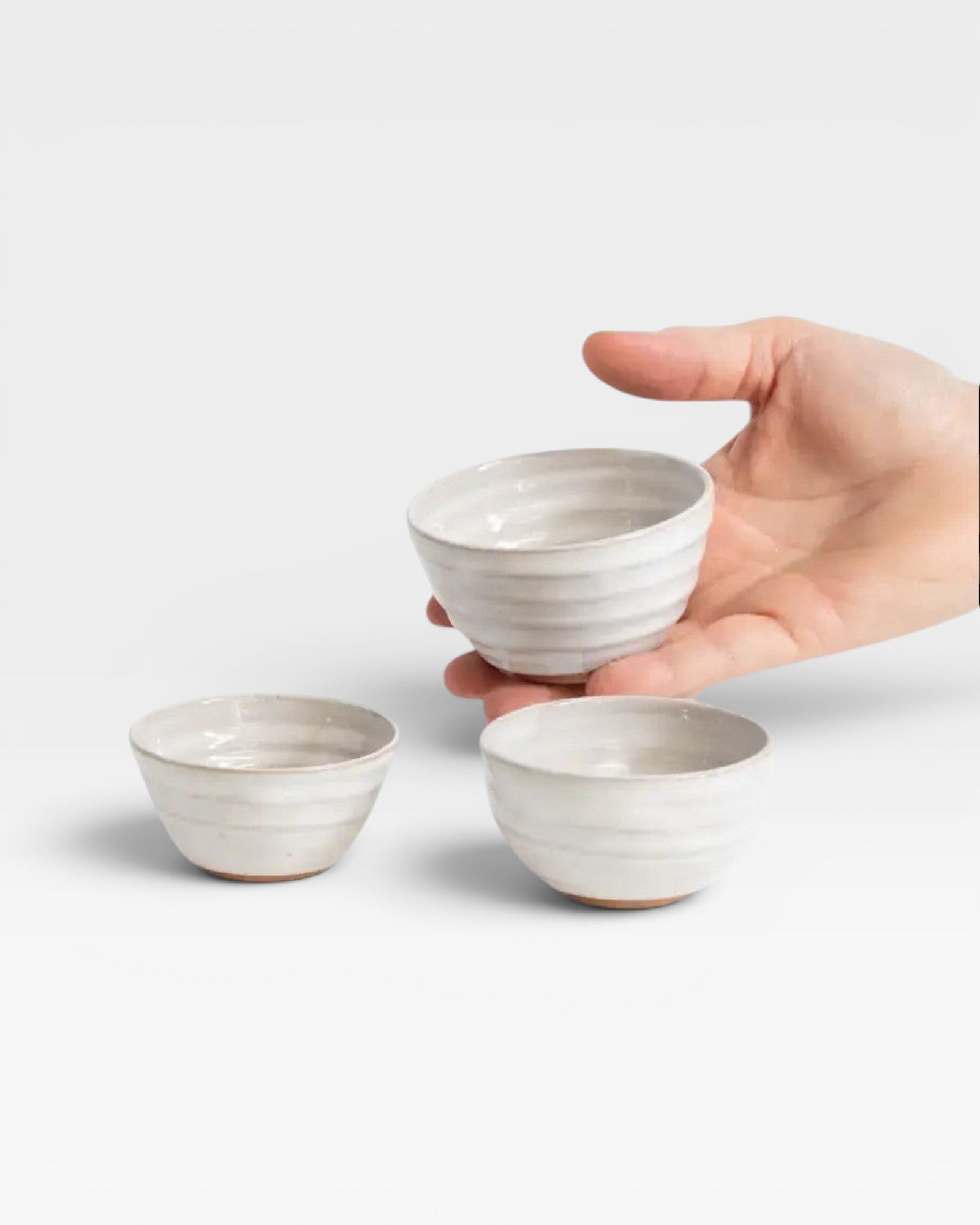 JONES + CO handcrafted off-white ceramic little bowls with ribbed texture held in a hand