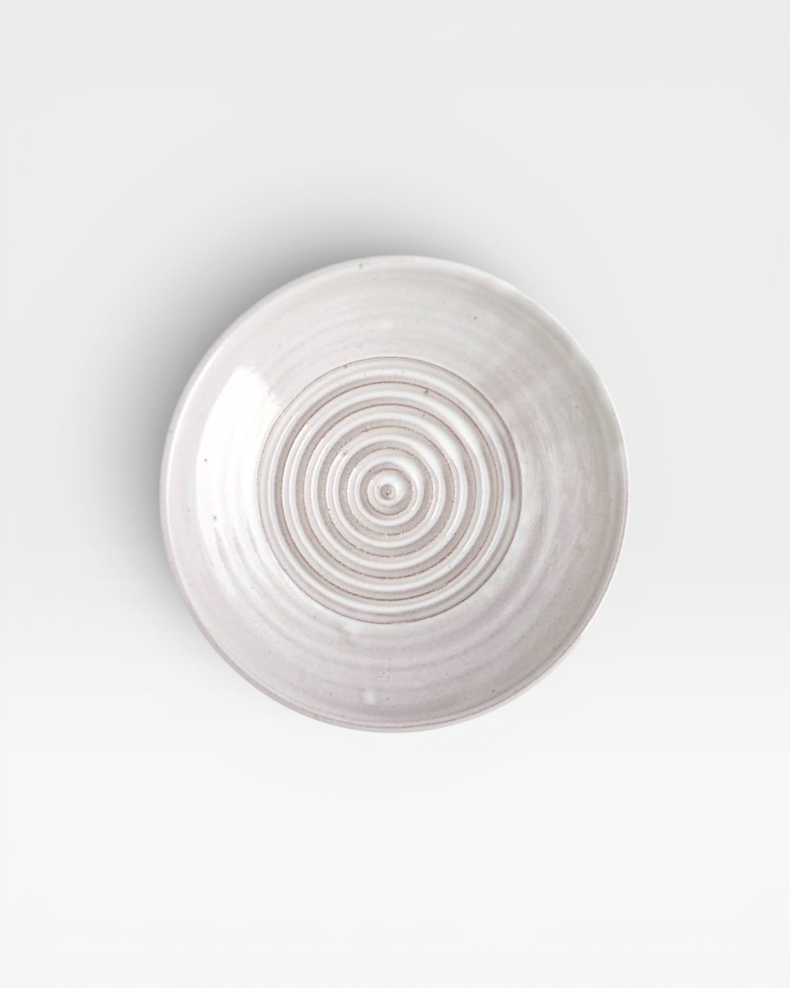 JONES + CO off-white ceramic garlic grater plate with a circular ridged center for grating garlic and herbs.