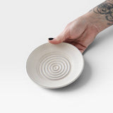JONES + CO off-white ceramic garlic grater plate with raised circular ridges held in a hand