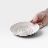 JONES + CO off-white ceramic garlic grater plate with raised spiral ridges held in a hand