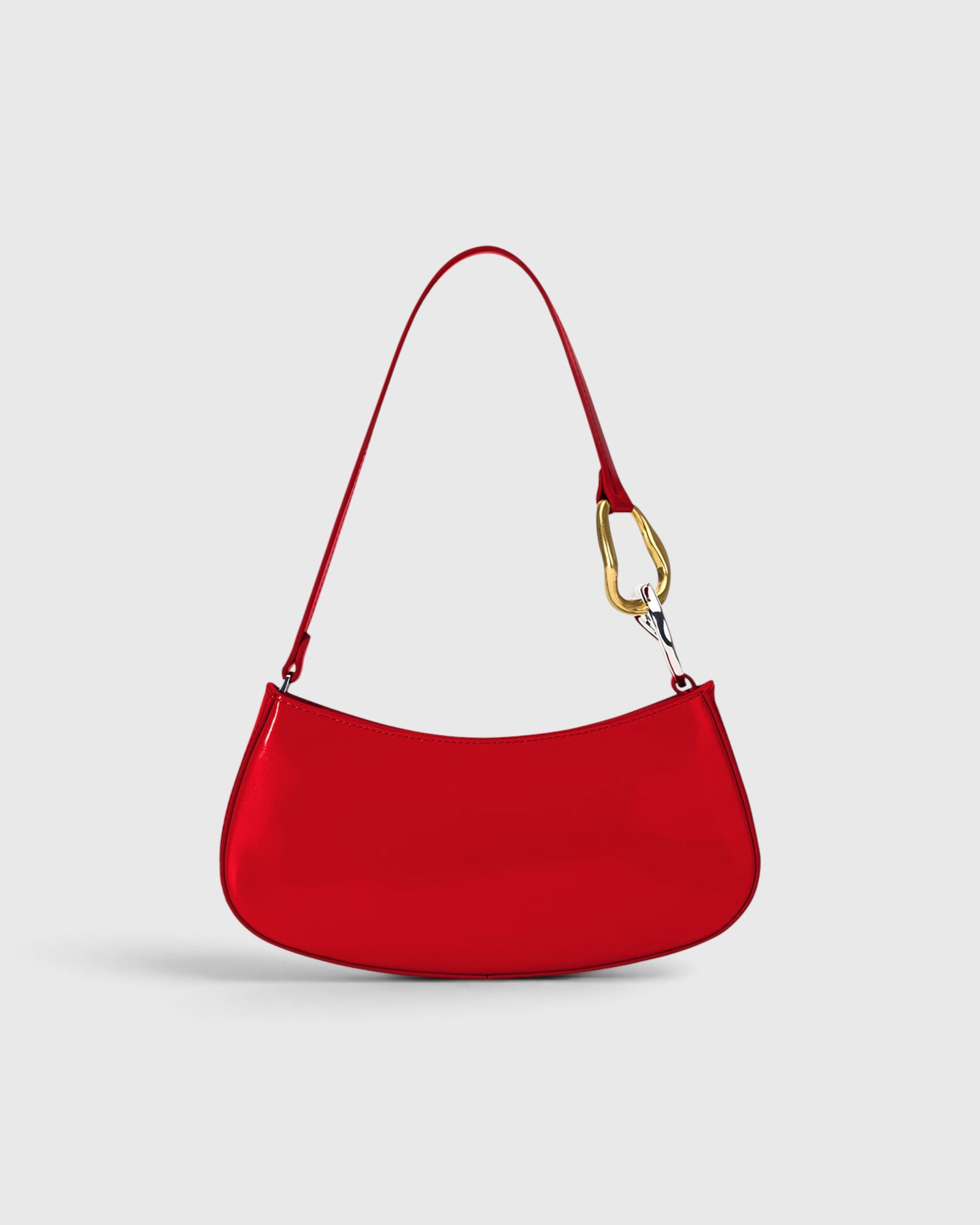 JONES + CO Ollie Bag in polished cherry-red leather with a crescent shape and gold and silver hardware strap detail.