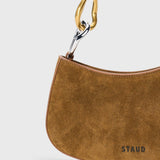 JONES + CO Ollie Bag in cigar tobacco suede with a curved crescent shape and two-tone gold and silver link strap.