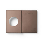 JONES + CO Open Journal with a brown fabric cover and a circular cutout on the front page, flat lay view.