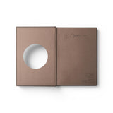 JONES + CO Open Journal with a brown fabric cover and a circular cutout on the front page, flat lay view.