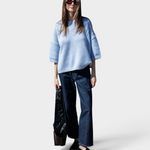 JONES + CO oversized heathered blue short sleeve sweater with dropped shoulders worn by a woman with dark jeans