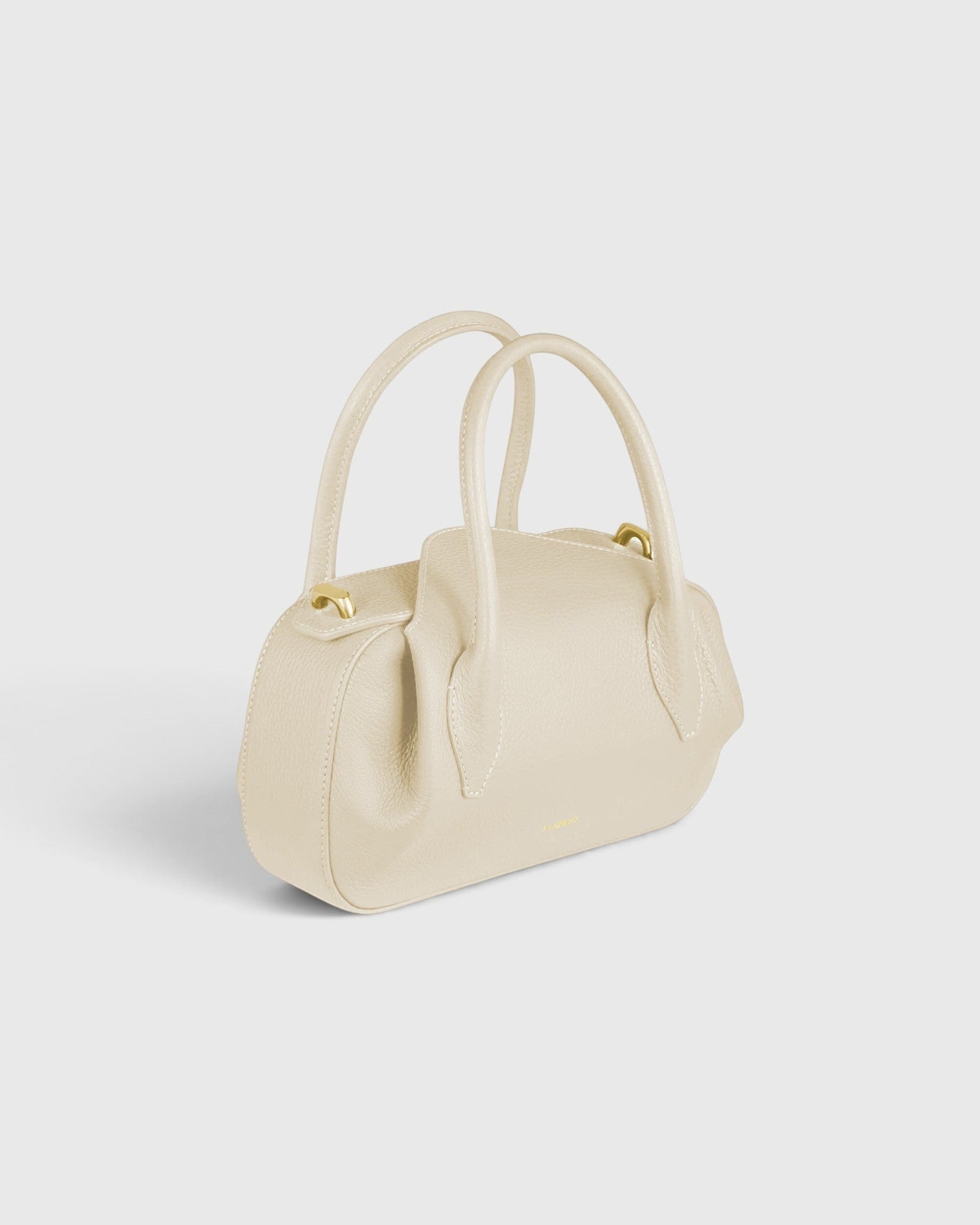 JONES + CO Oyster Mini Duffle in Angora pebble grained Italian leather with gold-tone hardware and top handles.