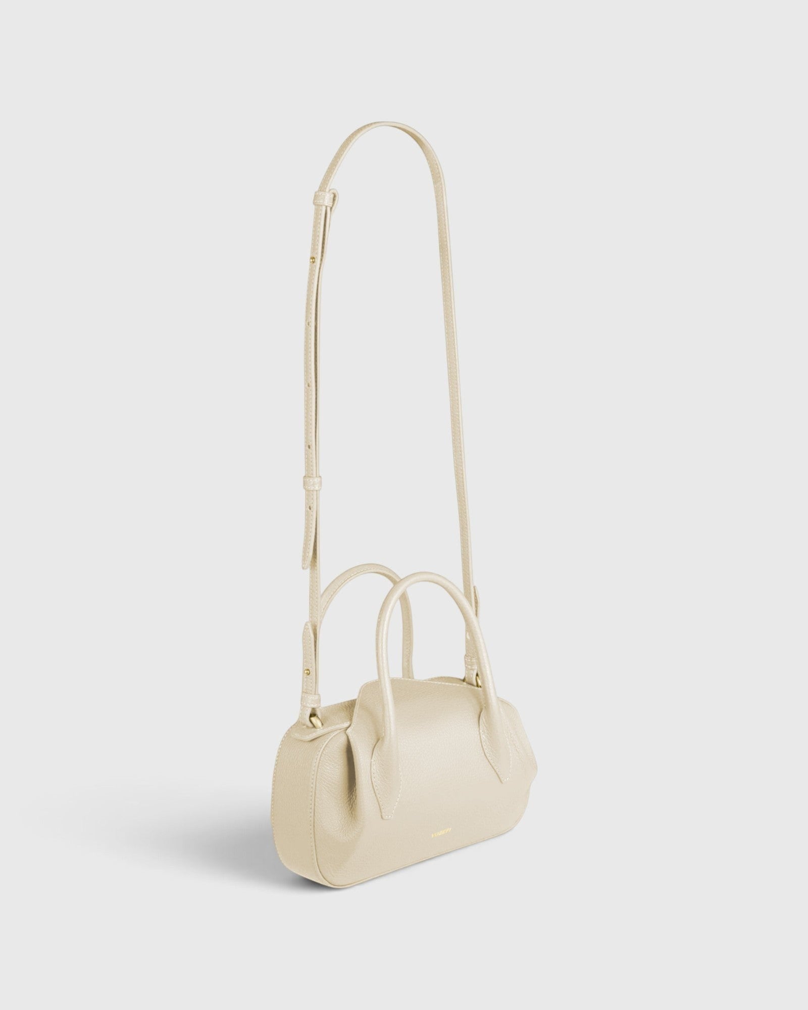 JONES + CO Oyster Mini Duffle in Angora pebble grained Italian leather with gold hardware and crossbody strap.