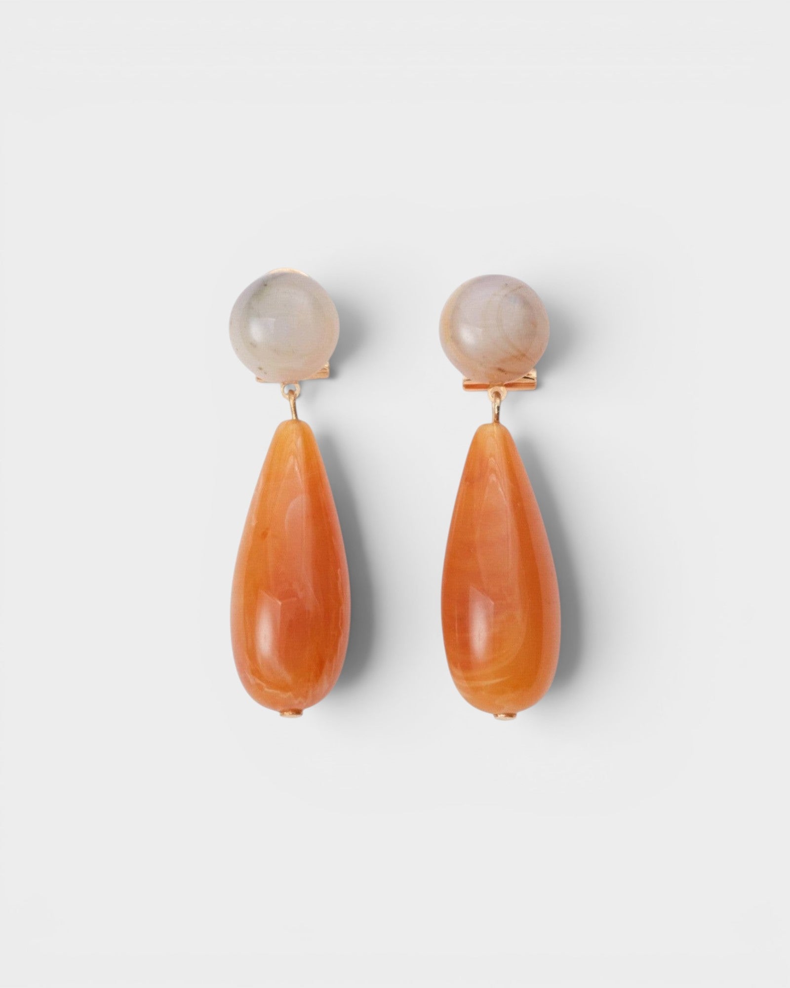 JONES + CO Pamploma sculptural acrylic earrings with cream spherical studs and orange tear-shaped drops.