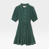 JONES + CO Phoebe short shirtdress in green Muir tartan featuring a ruffled collar, pearl buttons, and pintuck details.