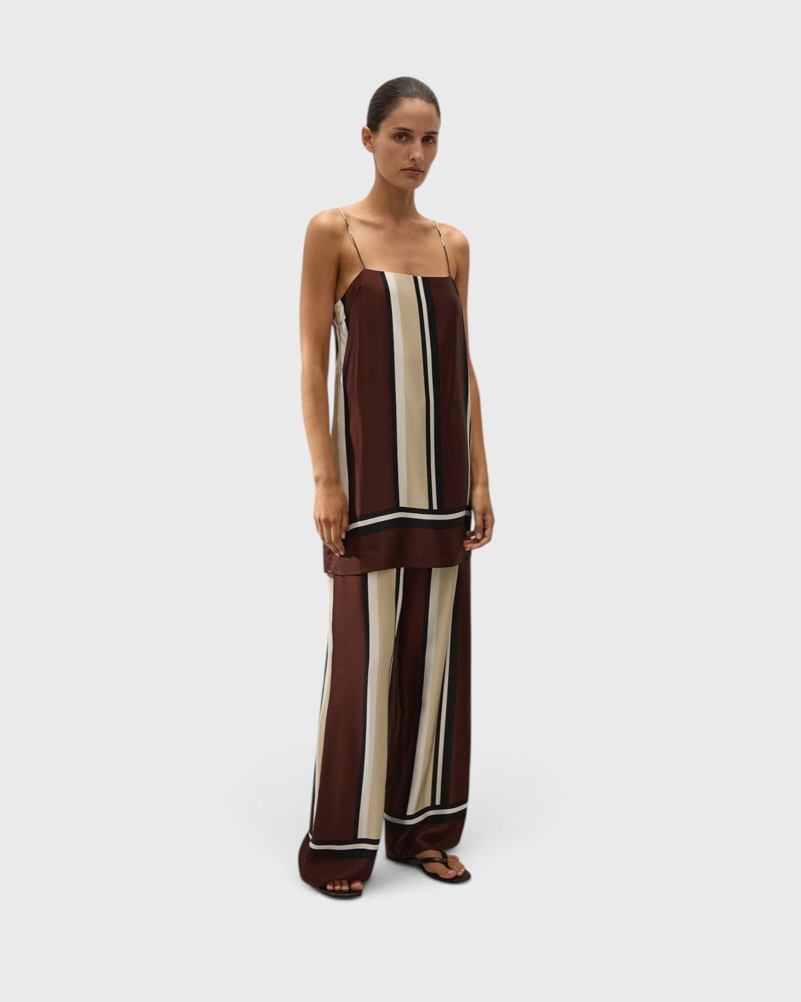 Model wearing JONES + CO Phylis mini slip dress in shiny brown and cream Sintra stripe viscose satin with thin straps
