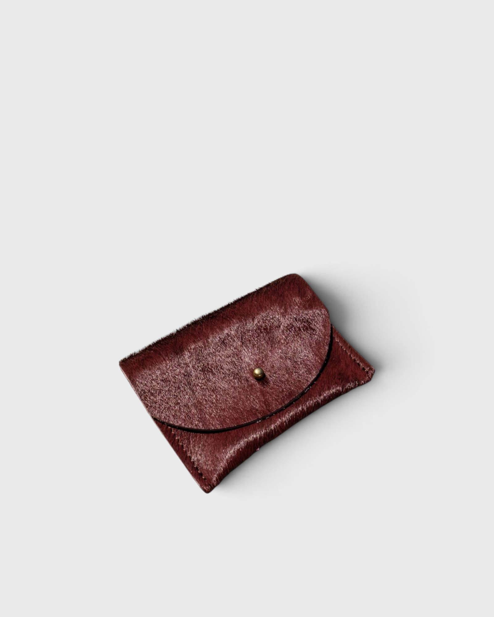 JONES + CO plum cowhide cardholder with a solid brass fastener, featuring a textured hair-on-hide finish.